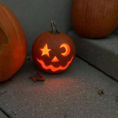 two pumpkins with faces carved into them sitting on the ground next to each other