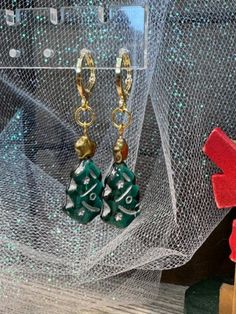 These delightful handmade dangle earrings are a festive addition to your holiday wardrobe. Featuring charming green Christmas tree charms adorned with gold stars, they evoke the magic of the season. Each earring is securely fastened with gold-plated round lever backs, ensuring comfort and elegance. Perfect for holiday parties or as a thoughtful gift, these earrings are a beautiful way to celebrate the joy of Christmas. Elegant Green Earrings For Christmas, Handmade Festive Earrings For Christmas, Handmade Gold Christmas Earrings, Green Holiday Earrings For Festive Occasions, Christmas Celebration Jewelry Drop Earrings, Christmas Dangle Jewelry For Celebration, Handmade Earrings For Holiday Festivities, Handmade Christmas Earrings For Celebration, Handmade Earrings For Holiday Celebrations