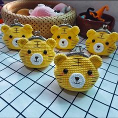 four yellow teddy bears are sitting on a table with other small items in the background