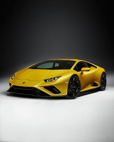 a yellow sports car parked in a dark room with white flooring and black rims