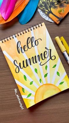 a notebook with the words hello summer written on it next to some feathers and markers