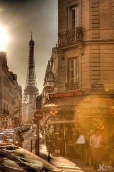 the eiffel tower is in the distance as cars drive down the street