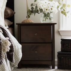 a bedroom with a bed, two nightstands and a vase filled with white flowers