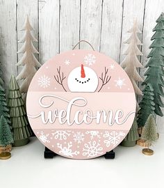 a sign that says welcome with snowflakes and trees in front of the board