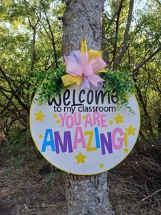 a welcome sign hanging from the side of a tree