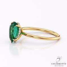 an oval shaped green stone with diamond accents on the side and sides, set in yellow gold