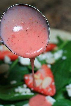 a spoon full of strawberry salad with spinach and feta cheese