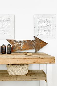 a wooden table topped with bottles next to two framed pictures