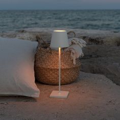 a lamp sitting on top of a rock next to a basket filled with pillows and blankets