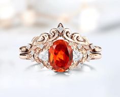 an orange stone surrounded by white diamonds in a gold ring on top of a table