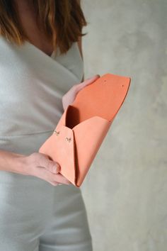 "Peach leather clutch for the entire day! This pastel orange envelope clutch is ideal to carry anything you might need during the day. A handmade clutch from Italian genuine nubuck leather. Our nubuck leather has a soft feel on the top but is firm enough to hold the shape of the bag. It resebles the suede feel of leather but it is even smoother to touch, like velvet. The clutch closes with two metal rivet studs in silver or gold. The pictures show the gold rivet studs. The interior is unlined. D Orange Envelope, Bridesmaid Clutches, Wedding Bags, Pastel Orange, Handmade Clutch, Leather Wedding, Leather Clutch Bag, Wedding Clutch, Envelope Clutch