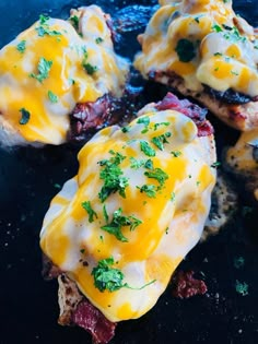 four pieces of bread with eggs and cheese on them sitting on a black table top