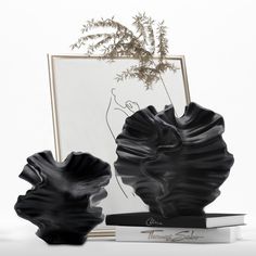 two black vases sitting next to each other on top of a white countertop