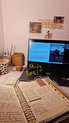 an open notebook sitting on top of a desk next to a laptop computer