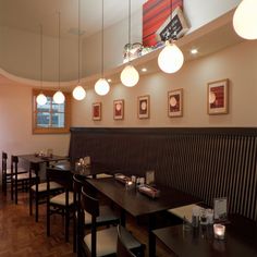 an empty restaurant with wooden tables and black benches, hanging lights and pictures on the wall