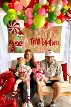 a man, woman and child sitting on a couch in front of balloons