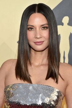 a woman in a strapless dress posing for the camera with her long dark hair