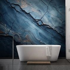 a white bath tub sitting in front of a blue and black marble wallpapered bathroom