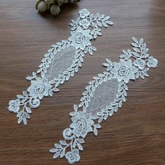 two pieces of white lace sitting on top of a wooden table