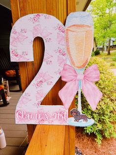 a wooden sign with the number twenty two and a wine glass on it, decorated with pink flowers