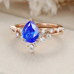 a ring with a blue tear shaped stone surrounded by white diamonds