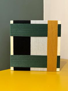 a yellow table with green, white and black striped material on the top of it