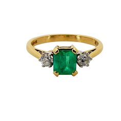 an emerald and diamond ring with three diamonds on the side, set in yellow gold