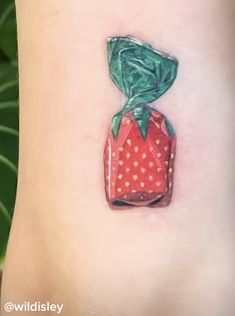 a strawberry with a green ribbon wrapped around it on the side of a woman's leg