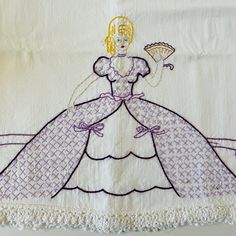 an embroidered piece of cloth with a woman in a purple dress holding a fan on it