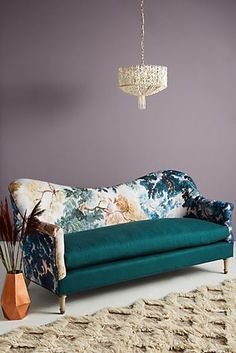 a living room with a blue couch and rugs on the floor next to a chandelier