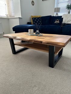 a wooden table sitting on top of a carpeted floor next to a blue couch