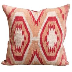 a red and white pillow with an intricate design on the front, sitting against a white background