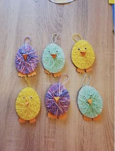 four little birds made out of yarn sitting on top of a wooden table next to each other