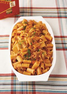 a white bowl filled with pasta and meat on top of a table next to a red box