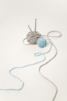 a ball of yarn and crochet hooks on a white surface with blue thread