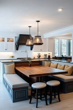 a kitchen with an island table surrounded by stools and lights over it's sink