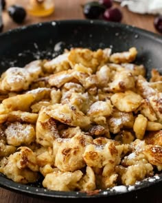 a pan filled with food on top of a wooden table covered in powdered sugar