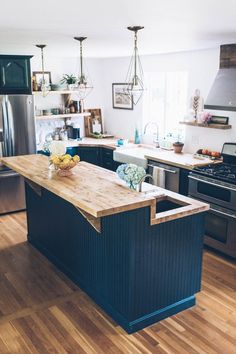 a large kitchen with an island in the middle and stainless steel appliances on both sides