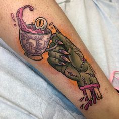 a person with a tattoo on their arm holding a cup and saucer in the shape of a hand