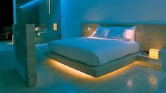 a large bed sitting inside of a bedroom next to a night stand with lights on it