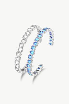 This silver bracelet set features two heart-shaped designed bangle bracelets with sparkling cubic zirconia accents, one with sky blue stones and the other with clear white stones. The heart shape symbolises love and affection, and the zirconia stones add a touch of sparkle and sophistication. The bangle bracelets are adjustable to fit any wrist size. They can be worn alone or stacked with other bracelets for a more dramatic look. This set of bangle bracelets is perfect for any outfit, special oc Silver Cubic Zirconia Heart Bangle Bracelet, Silver Cubic Zirconia Heart Bangle, Cubic Zirconia Heart Bangle Bracelet, Crystal Heart Bracelet For Anniversary, Light Blue Bangle Jewelry Gift, Light Blue Bangle Jewelry For Gift, Bracelet Set Silver, Love And Affection, White Stones