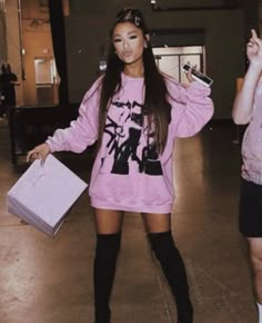 two young women standing next to each other in an empty room with one holding a purse and the other wearing thigh high socks