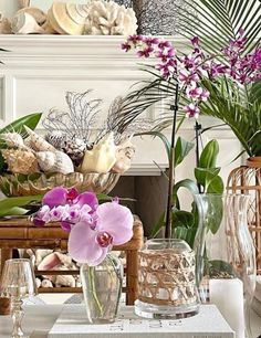 vases filled with purple flowers sitting on top of a table next to a fireplace