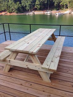 a picnic table sitting on top of a wooden deck next to a body of water