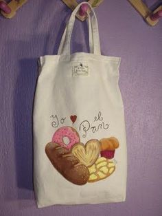 a tote bag hanging on a purple wall with donuts and muffins