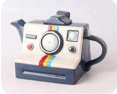 a polaroid camera shaped teapot with a rainbow stripe on the front and sides