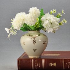 a vase with white flowers sitting on top of a book