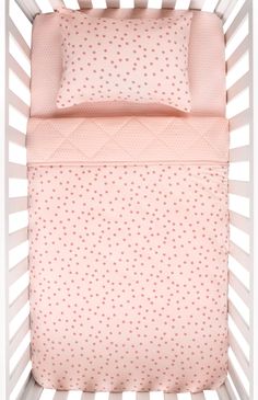 a baby crib with pink and white polka dot sheets