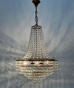 a chandelier hanging from the ceiling in front of a blue sky with clouds