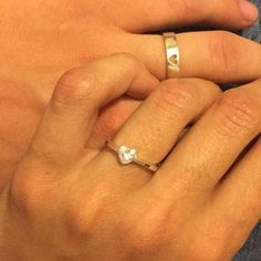 a woman's hand with two rings on her left and the other hand holding an engagement ring